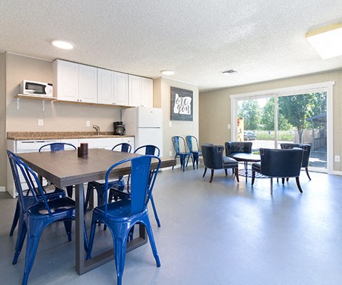a dining room with tables and chairs and a kitchen