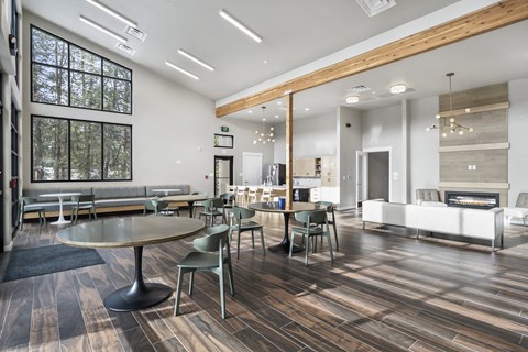 a communal area with tables and chairs and a living room with a fireplace