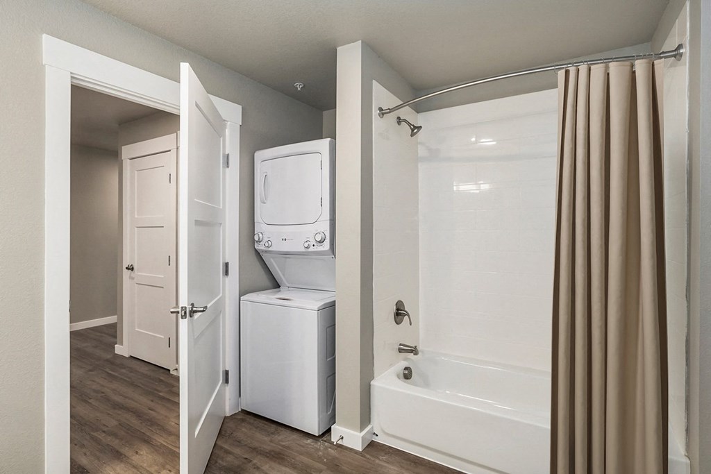 a bathroom with a washer and dryer in it and a shower and tub