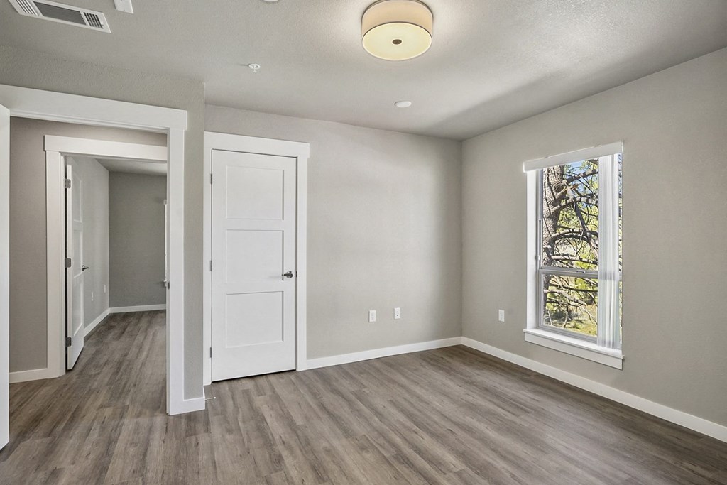 an empty room with hardwood floors and a large window