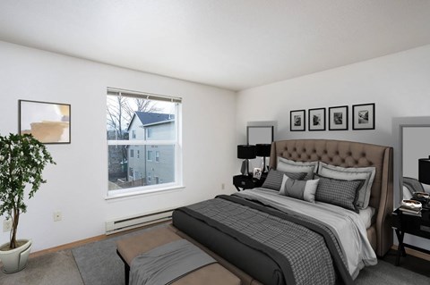 A bedroom with a large bed and a potted plant.