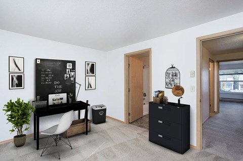 A black desk with a white chair and a black cabinet with a plant on top.