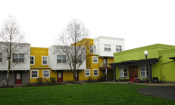 a row of colorful houses in front of a green yard