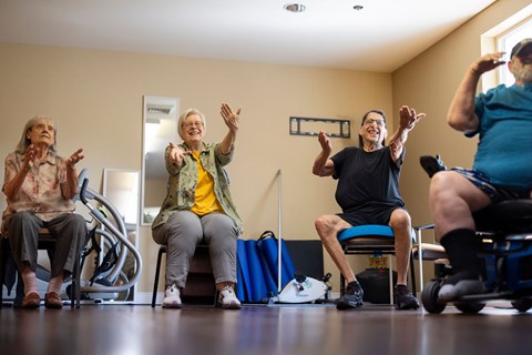 Four elderly people are exercising in a gym.
