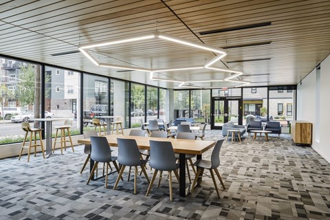A modern dining area with wooden tables and grey chairs.