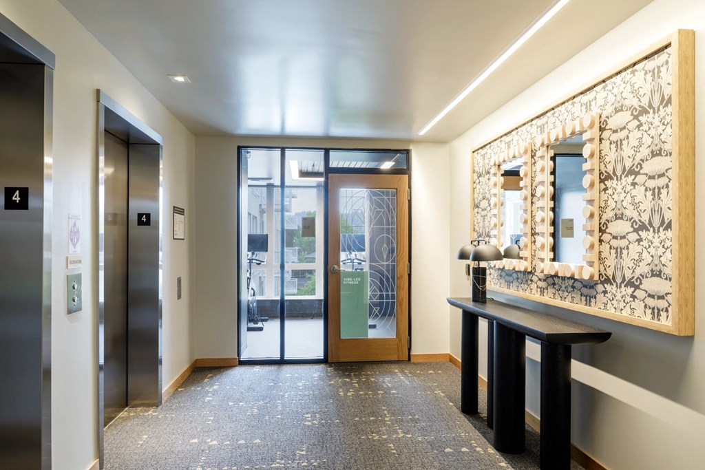a lobby with glass doors and a mirror and a table