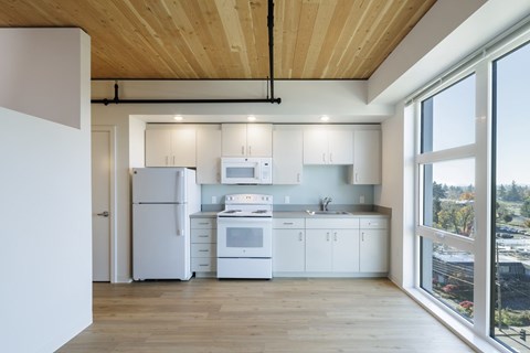 A modern kitchen with white appliances and wooden floors.