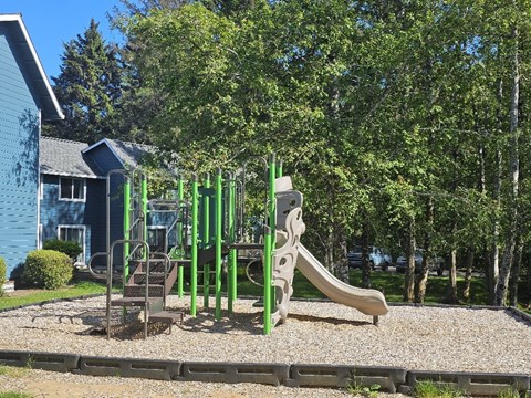 A playground with a green slide and a brown slide.