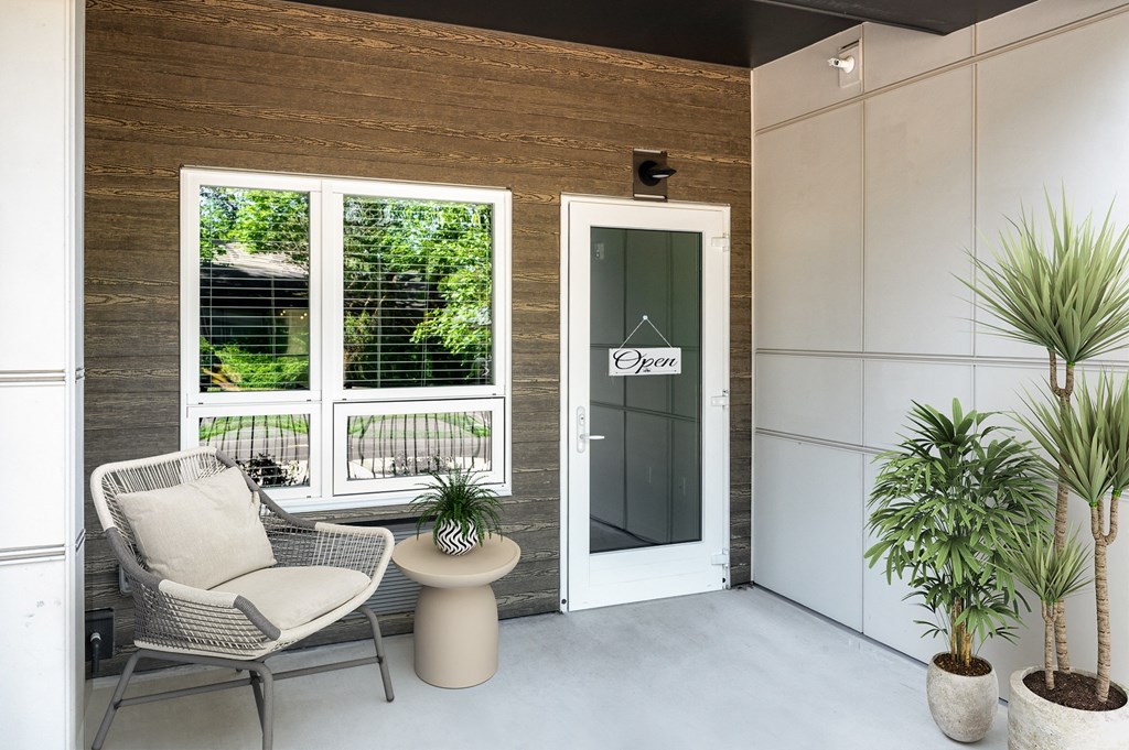 a porch with two chairs and a table and a door