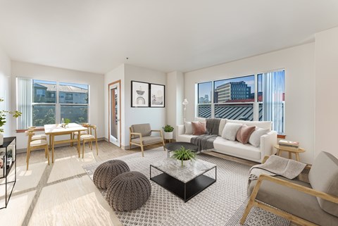 A living room with a white couch, a coffee table, and a dining table.