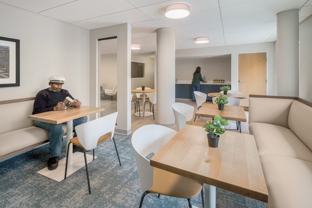a man sitting at a table in a room with a couch and tables