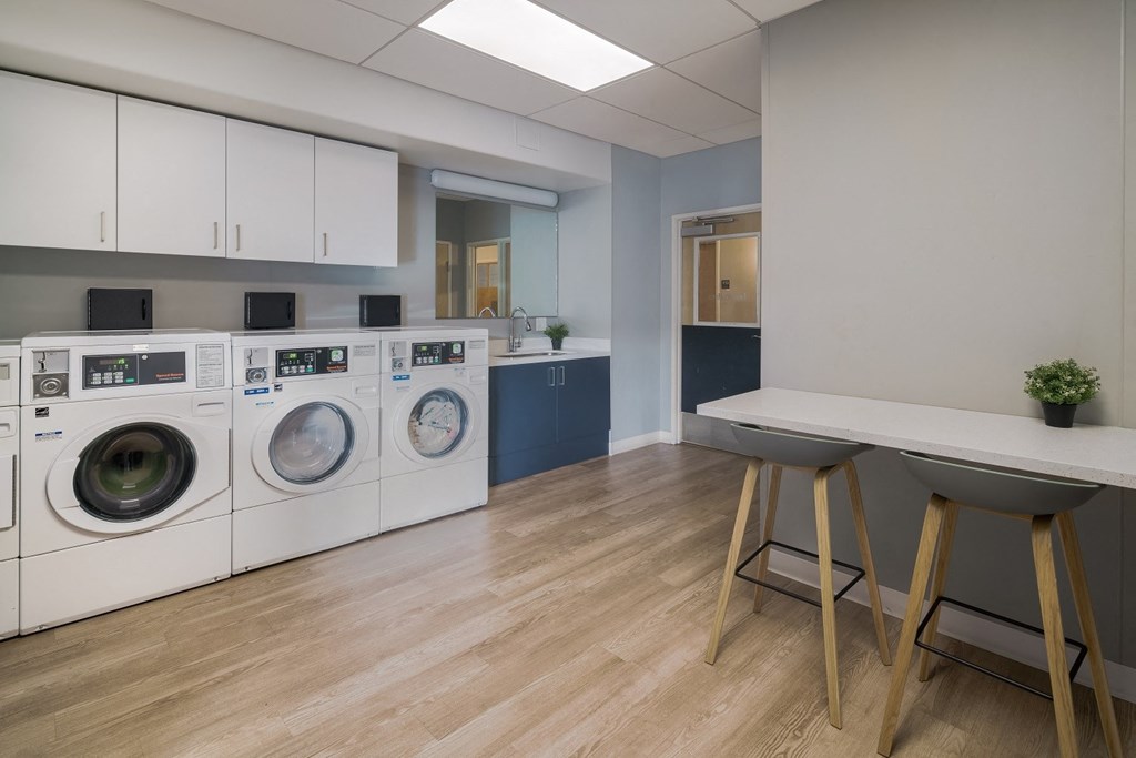 a laundry room with washers and dryers and a table with stools