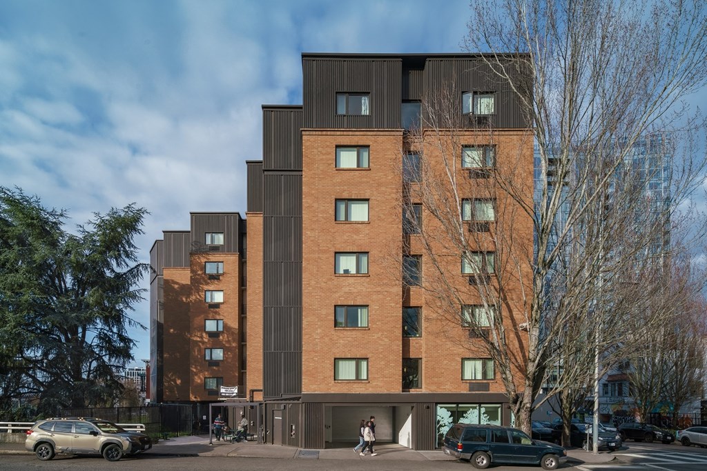a tall brick building with a black facade and people walking in front of it