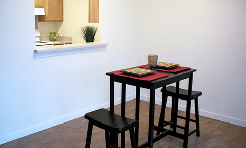 a small table and three stools in a room with a white wall