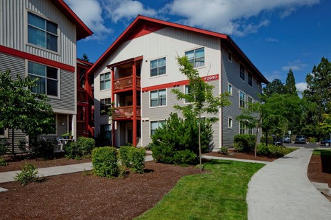 A modern building with a red roof and a white facade with a red stripe down the center.