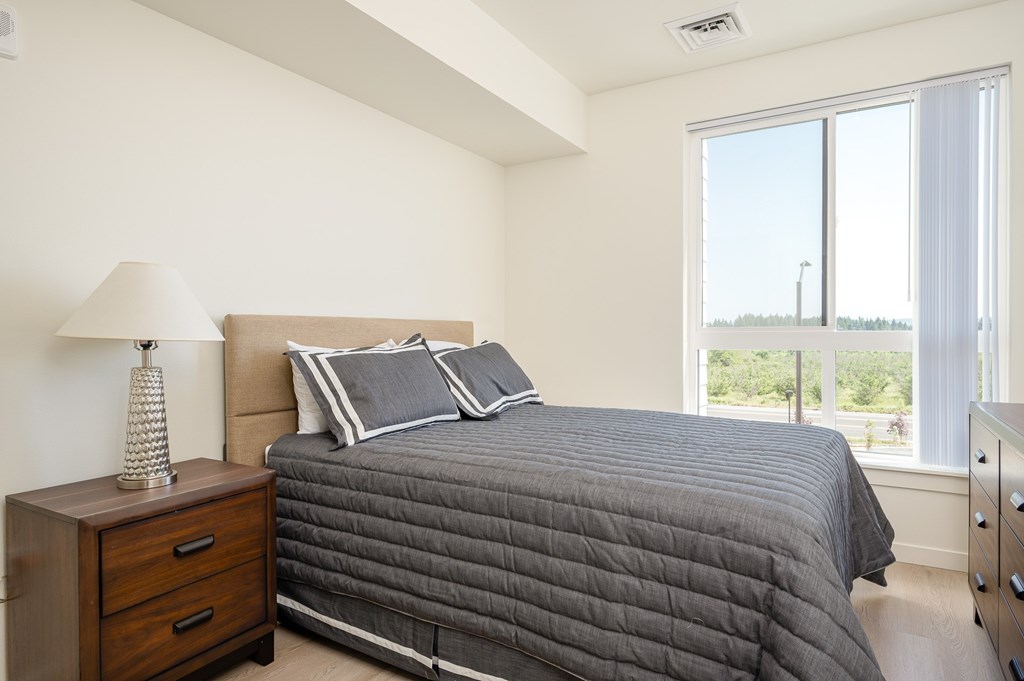 A bedroom with a large bed and a lamp on a nightstand.