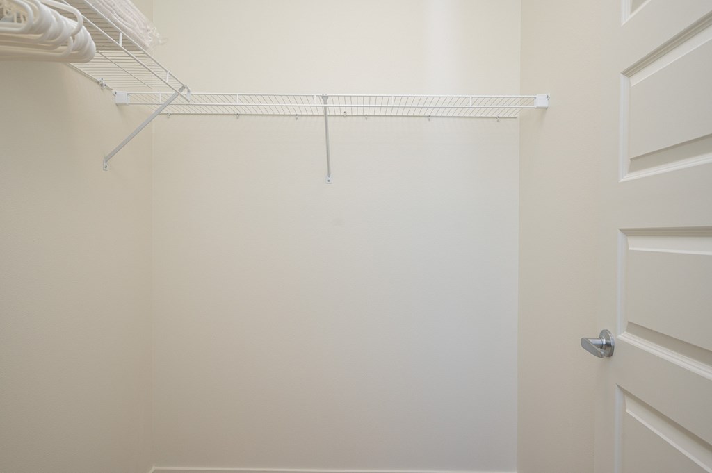 A white closet with a door and a shelf.