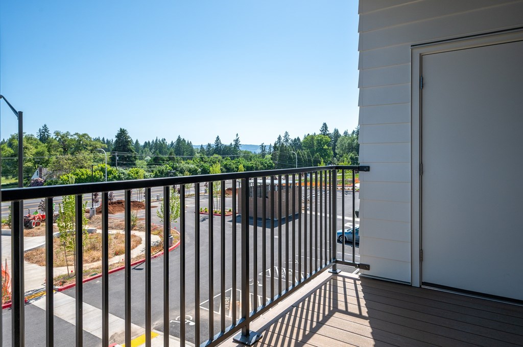 A balcony with a view of a road and trees.