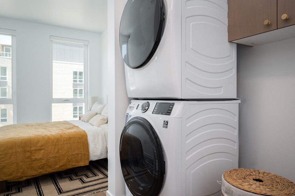 a bedroom with a washing machine and a bed with a washer and dryer