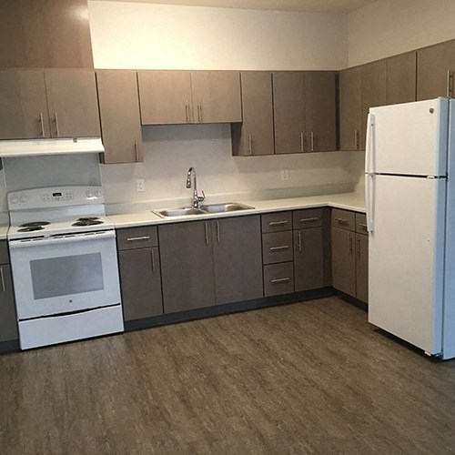 an empty kitchen with a stove refrigerator and sink