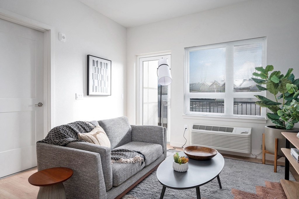 a small living room with a gray couch and a round coffee table