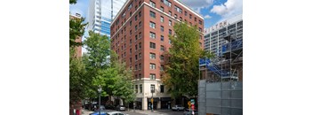 a tall red brick building on the corner of a city street