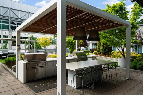 A white outdoor kitchen with a grill and table.