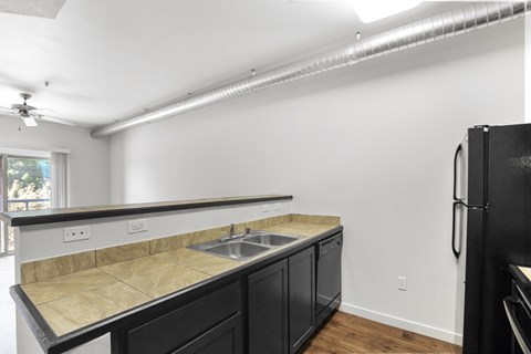 A kitchen with black cabinets and a granite countertop.