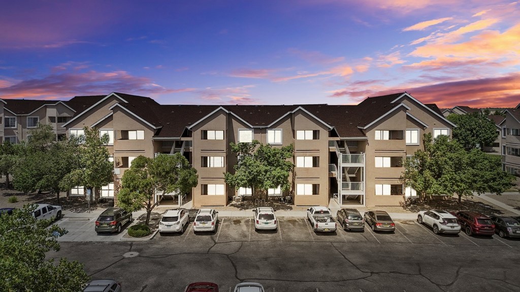 A large apartment complex with a parking lot in front.