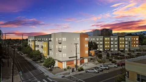 A sunset view of a street with cars and buildings.