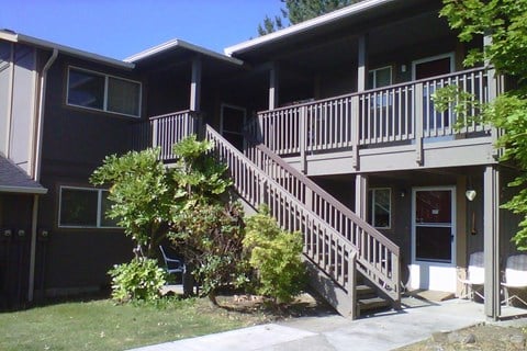 A brown house with a deck and stairs leading to the front door.