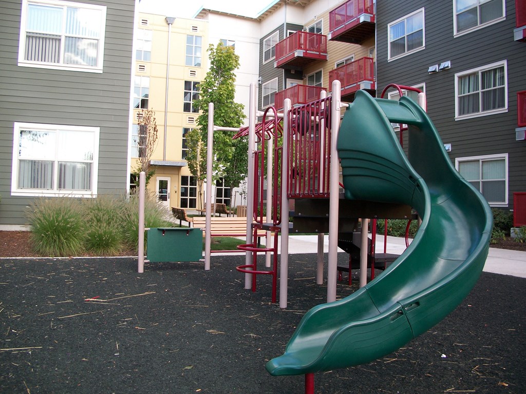 a playground with a slide in front of an apartment building