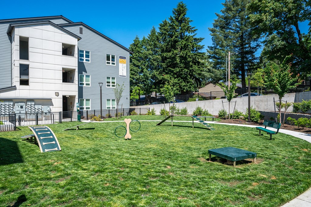 a yard with a swing set and a bench in front of a building