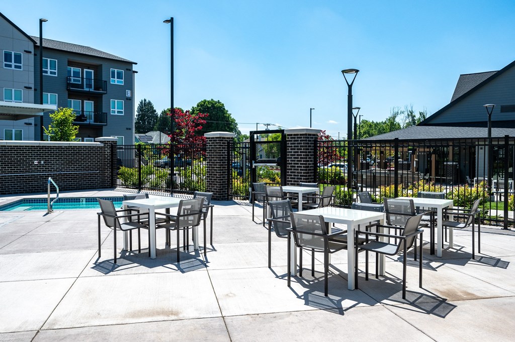 an outdoor patio with tables and chairs next to a swimming pool