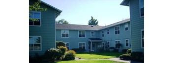 Apartment complex with green lawn and trees in the background.