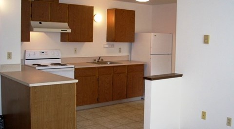 A kitchen with wooden cabinets and a white fridge.