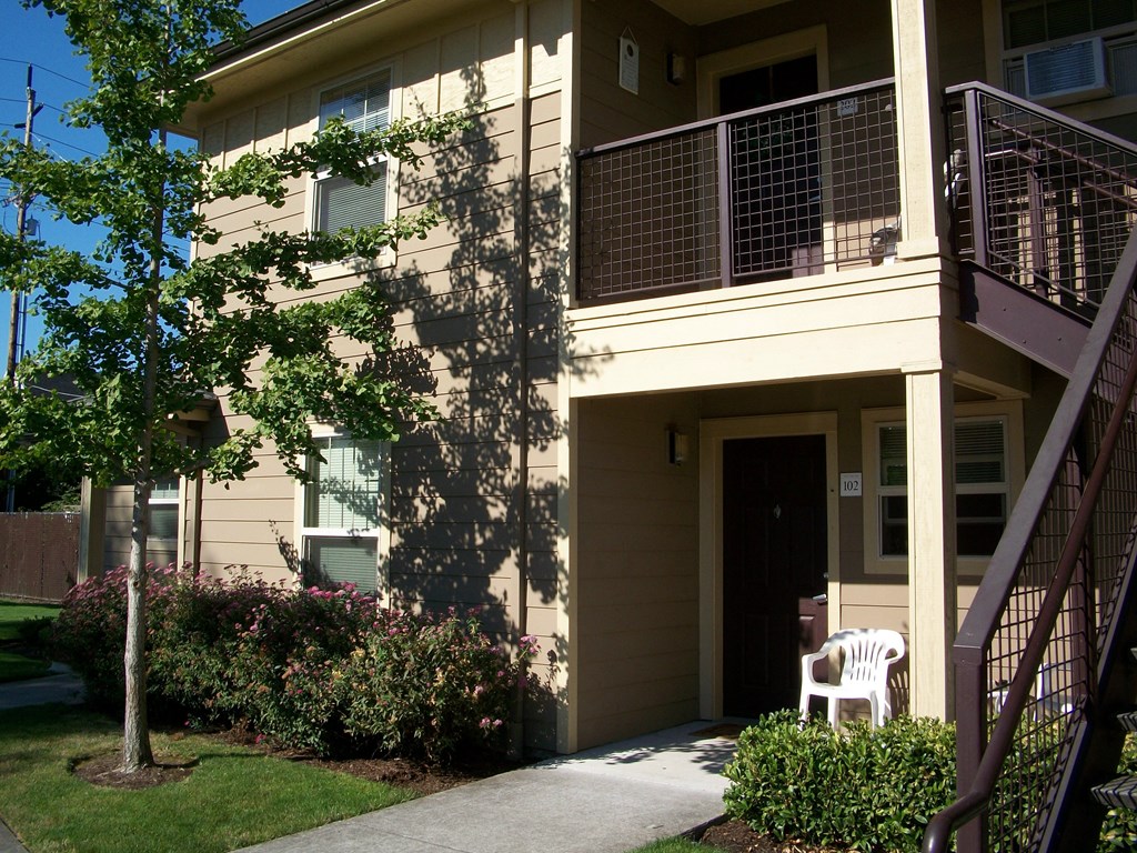 an exterior view of a building with a porch and a chair on the sidewalk