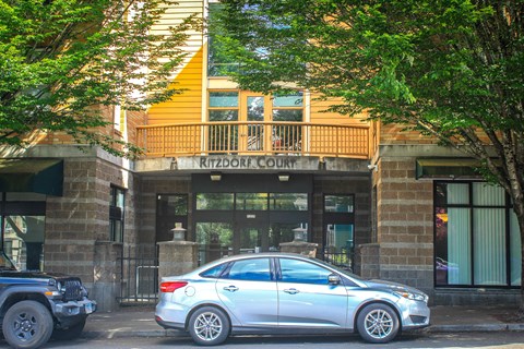 A silver car is parked in front of a building with the sign "Ritzboro Court".