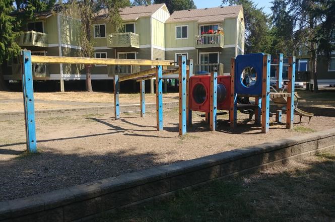 A playground with a blue swing set and red and blue play equipment.