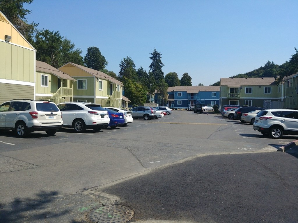 A parking lot with cars and apartment buildings in the background.