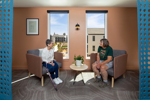 Two people sitting in a room with orange walls.