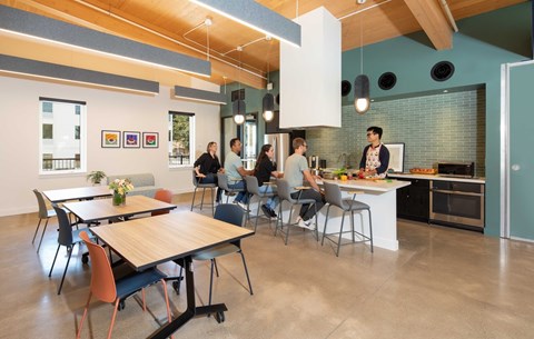 A group of people are sitting around a table in a modern kitchen.