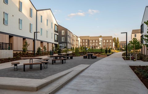 A long concrete walkway leads between two rows of modern buildings.