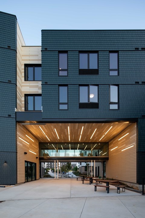A modern building with a black facade and a wooden entrance.