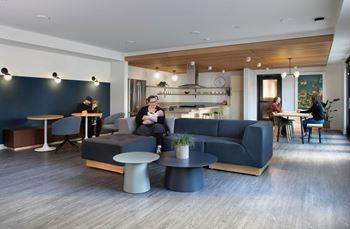 A woman is sitting on a couch in a modern living room.