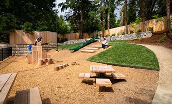 A playground with a green slide and wooden benches.