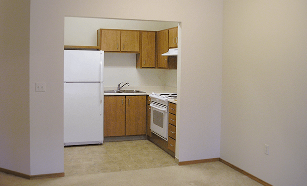 an empty kitchen with a white refrigerator and a sink