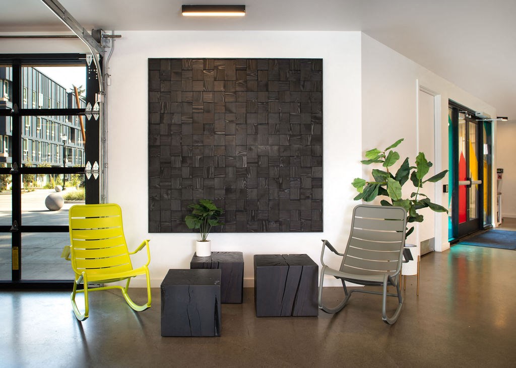 a black brick wall in the middle of a room with two yellow chairs in front of it