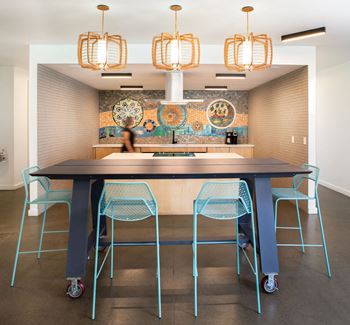 a large table with blue chairs in front of a mosaic wall