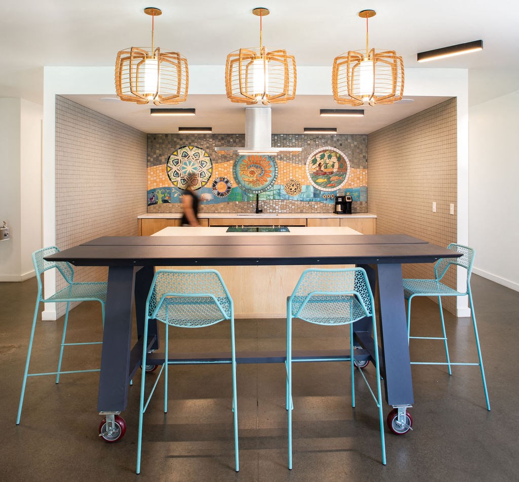 a large table with blue chairs in front of a mosaic wall